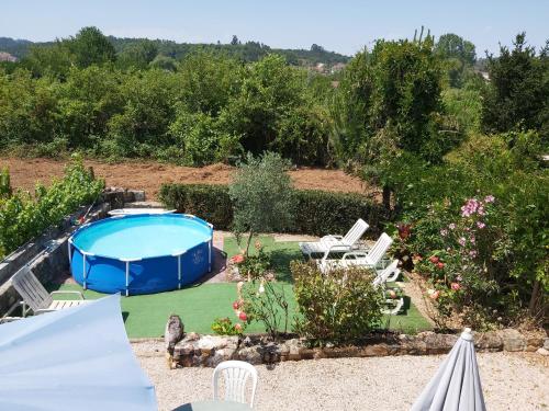 a backyard with a swimming pool and a lawn with chairs at Casa de Alagoa in Arganil