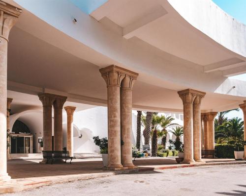 una fila di colonne in un edificio con palme di Kanta Resort and Spa a Sousse