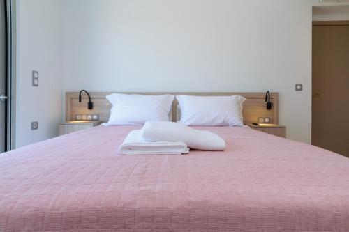 Una cama rosa con dos almohadas encima. en Katakis LuxuryVillas, en La Canea