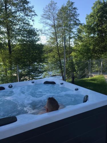 una persona en un jacuzzi en un patio en Hotel Rezydencja Mazury SPA & Lake, en Mrągowo