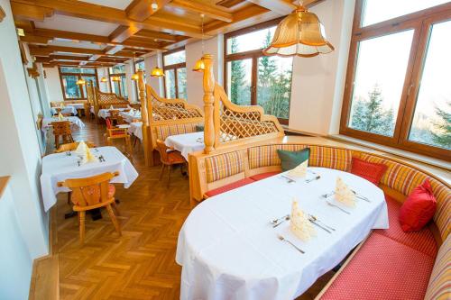 un ristorante con due tavoli, sedie e finestre di Kurhotel Renona Rehabilitation a Semmering