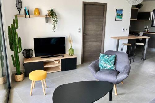 uma sala de estar com uma televisão, uma cadeira e uma mesa em Appartement Stanatura - Standing - Proche du port - 4 personnes - 1 chambre em Porto-Vecchio