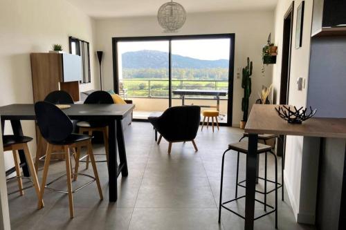 uma sala de estar com cadeiras e mesas e uma grande janela em Appartement Stanatura - Standing - Proche du port - 4 personnes - 1 chambre em Porto-Vecchio