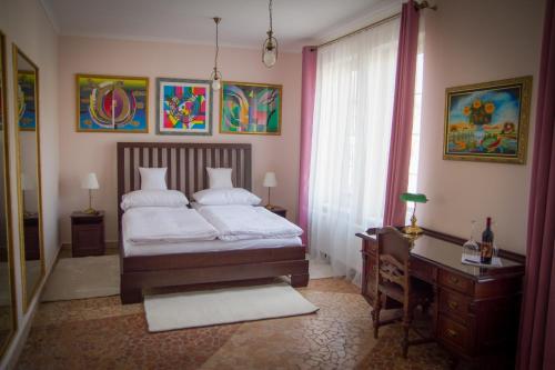 a bedroom with a bed and a desk and a window at Hotel Bojnický vínny dom in Bojnice