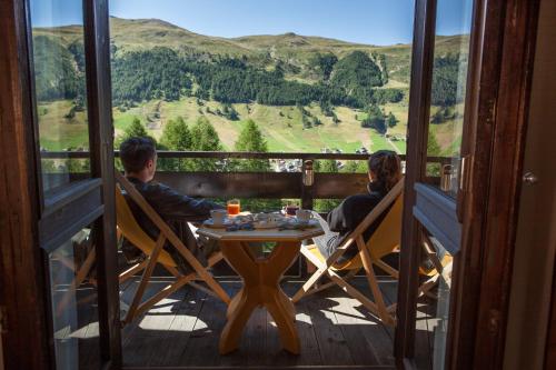 dois homens sentados numa mesa numa varanda com vista em Hotel Intermonti em Livigno