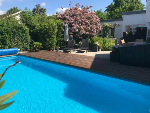 una piscina con terrazza in legno accanto a una casa di Kathrines Bed & Breakfast a Svendborg