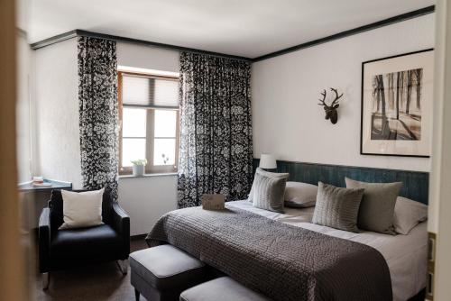 a bedroom with a bed and a chair and a window at Sommers Hotel Altes Posteck in Reichenbach im Vogtland