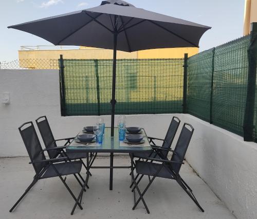 una mesa con sillas y una sombrilla en el patio en La Casita Blanca, en El Astillero