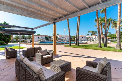 patio z krzesłami, parasolem i palmami w obiekcie Apartamentos Vistapicas w mieście Cala en Blanes