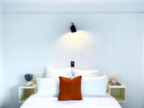 a bed with white pillows and a orange pillow on it at Relais Des Villards in Séez