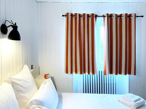 a bed with orange and white curtains and a window at Relais Des Villards in Séez