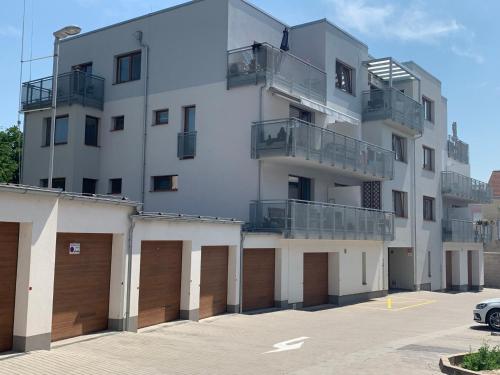 Kellerův mlýn - Apartmán s vlastní garáží, Znojmo centrum في زنويمو: مبنى ابيض فيه بابين جراج وموقف سيارات