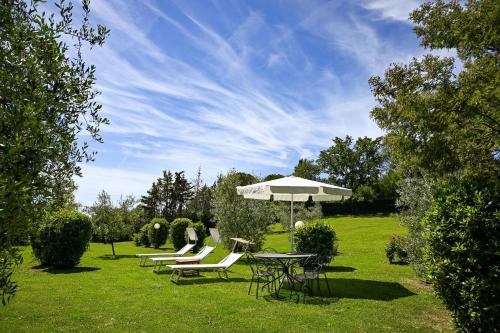 uma mesa e cadeiras e um guarda-sol num quintal em B&B Villa Giulia em Saturnia