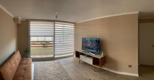 sala de estar con TV y ventana grande en Acogedor depto en barrio residencial, La Serena, en La Serena