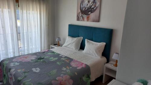 een slaapkamer met een bed met een blauw hoofdeinde bij Casa Luar in Odeceixe