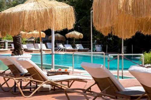 een groep stoelen en parasols naast een zwembad bij Montespina Park Hotel in Napels