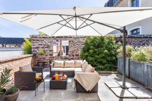 a patio with a white umbrella and chairs and tables at Maison Sévigné - Le calme du Thabor et la proximité du centre ville in Rennes