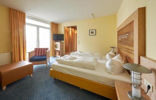 una habitación de hotel con una cama grande y una silla en Strandhotel VierJahresZeiten, en Borkum