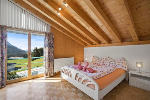 um quarto com uma cama e uma grande janela em Golden Peaks Ferienhaus Valbella-Lenzerheide em Valbella