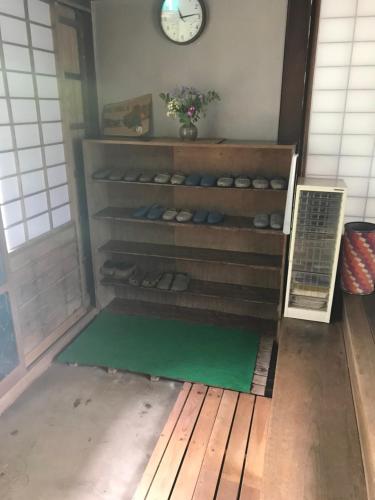 een kamer met een plank met schoenen en een klok bij Taikoji Shukubo Hostel in Ise