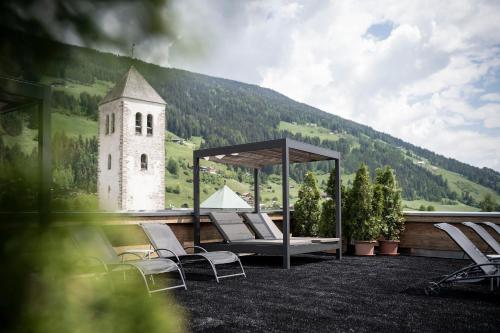 - un groupe de chaises et un kiosque avec une tour d'horloge dans l'établissement Post Hotel - Tradition & Lifestyle Adults Only, à San Candido