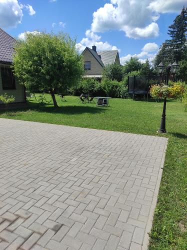 Una pasarela de ladrillo en un patio con un árbol en Atostogų namai, en Druskininkai