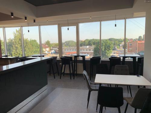 a restaurant with tables and chairs and large windows at Red Cube Hotel in Kamianets-Podilskyi