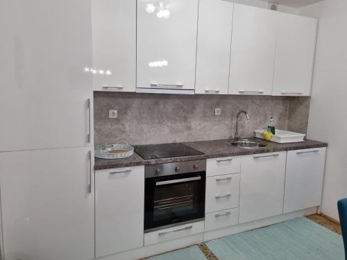 una cocina con armarios blancos y fregadero en Apartman Nataly, en Varaždin