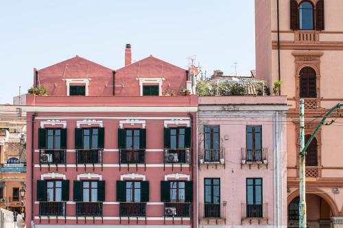 um edifício cor-de-rosa com janelas pretas numa cidade em Right House Sur le Port - Harbour View em Cagliari