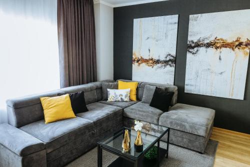 uma sala de estar com um sofá cinzento e almofadas amarelas em Charlotte Apartment - 2Bedrooms w Parking near Nymphaea em Oradea