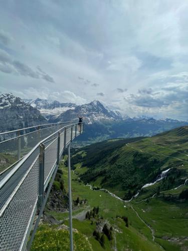 un ponte tra le montagne con una persona sopra di Almis Sunna a Grindelwald