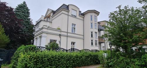 ein großes weißes Haus mit einer Hecke davor in der Unterkunft Ferienwohnung in Villa in Stralsund