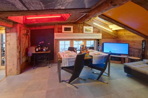 a dining room with a table and a tv at Chalet Schtuba in Zermatt