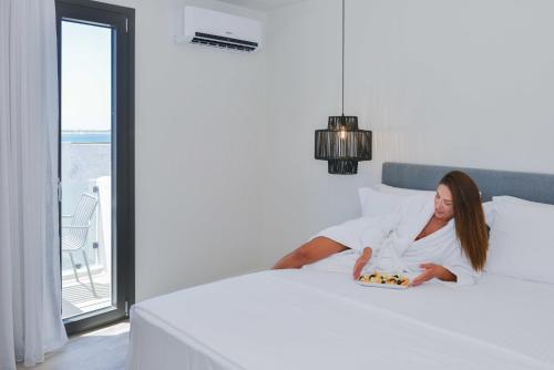 Una donna sdraiata su un letto con un regalo di Princess Mare Hotel - Adults Only a Naxos Chora