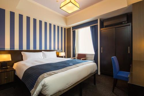 una camera d'albergo con letto e sedia blu di Hotel Monterey Kyoto a Kyoto