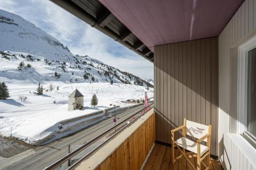 a chair on a balcony with a view of a snow covered mountain at Hotel Alpina in Obertauern