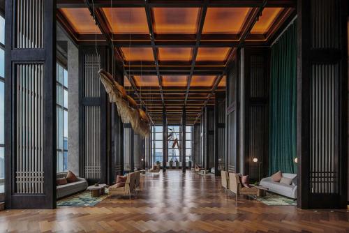 vestíbulo de un edificio con sofás y ventanas en Grand Bay Hotel Chengdu, en Chengdú