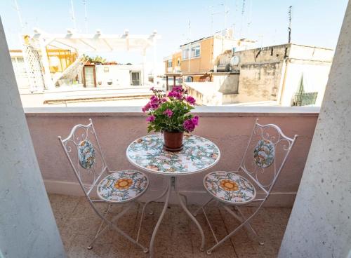 una mesa con un jarrón de flores en el balcón en Porto Antico, en Bari