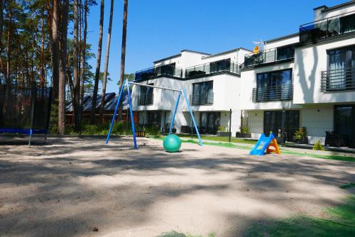 un parque infantil con columpio frente a un edificio en Apartamenty Marco Polo, en Dziwnówek