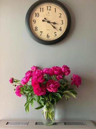 um relógio numa parede acima de um vaso de flores cor-de-rosa em Sunny Hotel em Lviv