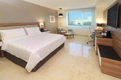 a large bedroom with a large bed and a television at Holiday Inn & Suites - Puerto Vallarta Marina & Golf, an IHG Hotel in Puerto Vallarta