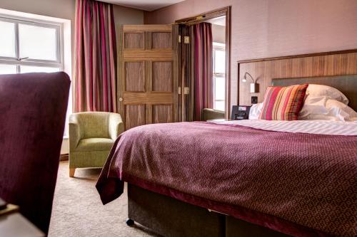 ein Hotelzimmer mit einem Bett und einem Stuhl in der Unterkunft Ballygally Castle in Larne