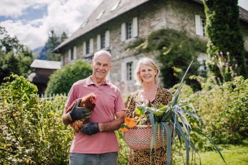 Um homem e uma mulher num jardim com galinhas. em Hotel Mas de la Coutettaz, The Farmhouse em Morzine