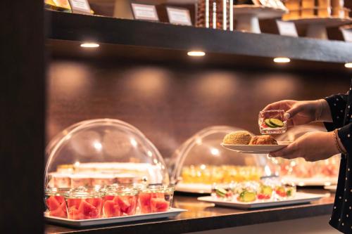 una persona sosteniendo un plato de comida detrás de un mostrador en Le Grand Hotel, en Estrasburgo