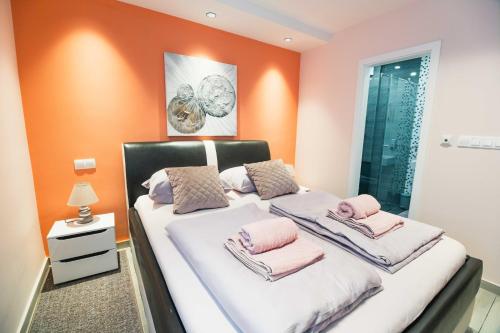 a bedroom with orange walls and a bed with pink towels at The Place Apartments Hebrangova in Zagreb