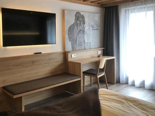 a bedroom with a desk and a television and a bed at Landhotel Kaserer in Bramberg am Wildkogel