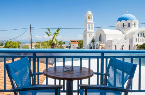 une table et deux chaises sur un balcon avec une mosquée dans l'établissement Saronis Hotel Agistri - Adults Only, à Skala