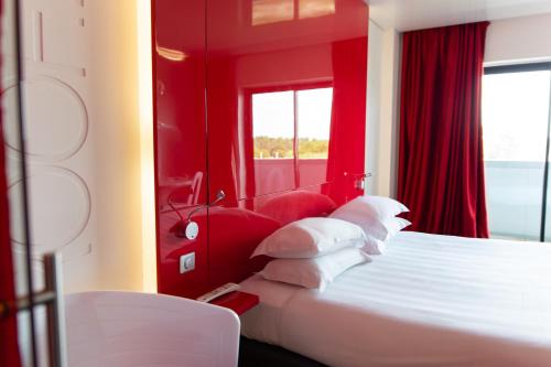 1 dormitorio con paredes rojas y 1 cama con almohadas blancas en Zenitude Hôtel Résidences Bassin d'Arcachon, en La Teste-de-Buch