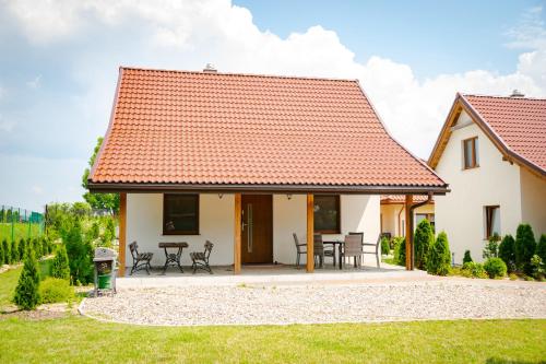 une maison blanche avec un toit rouge dans l'établissement Mazurskie El Dorado, à Mikołajki