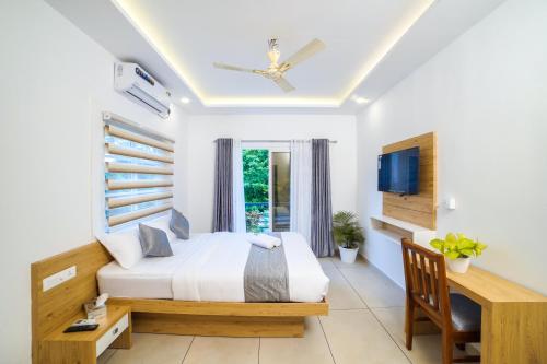 una camera con letto, scrivania e TV di Oceana Hills Residency a Alleppey